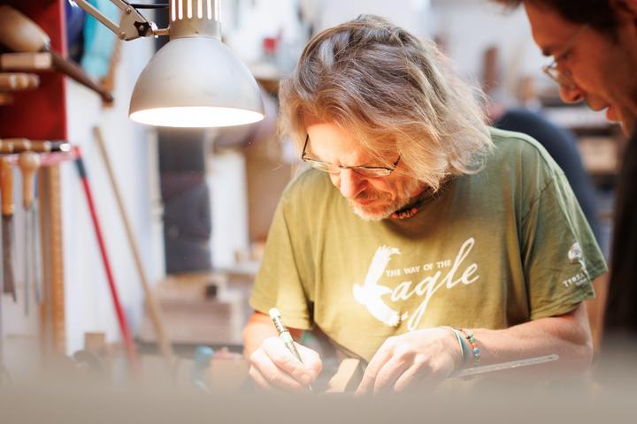Joe Knauer zeichnet unter der Werkstattlampe am Bogenholz an